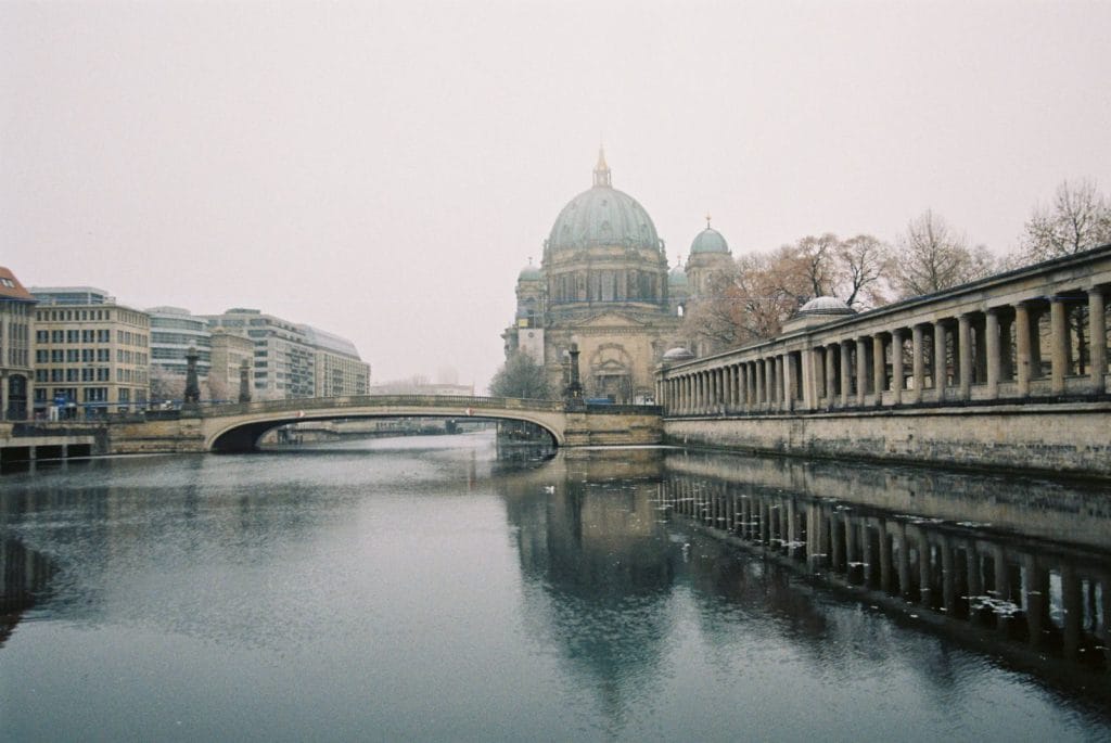 A serene view of Berlin Cathedral and a historic bridge enveloped in fog, showcasing urban architecture.