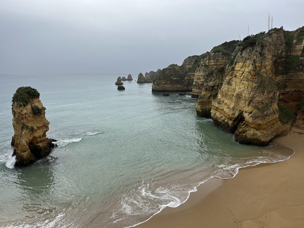 Rugged coastal landscape with sea stacks and sandy beach near Lagos, Faro, Portugal, February 2025
