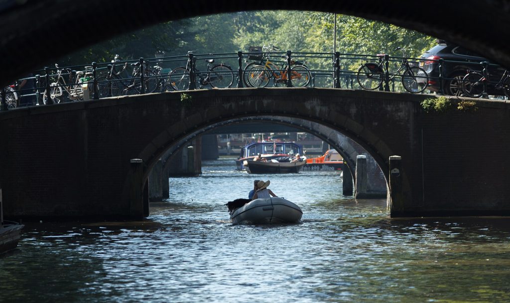 Canal boat travelling beneath a brick bridge in Amsterdam