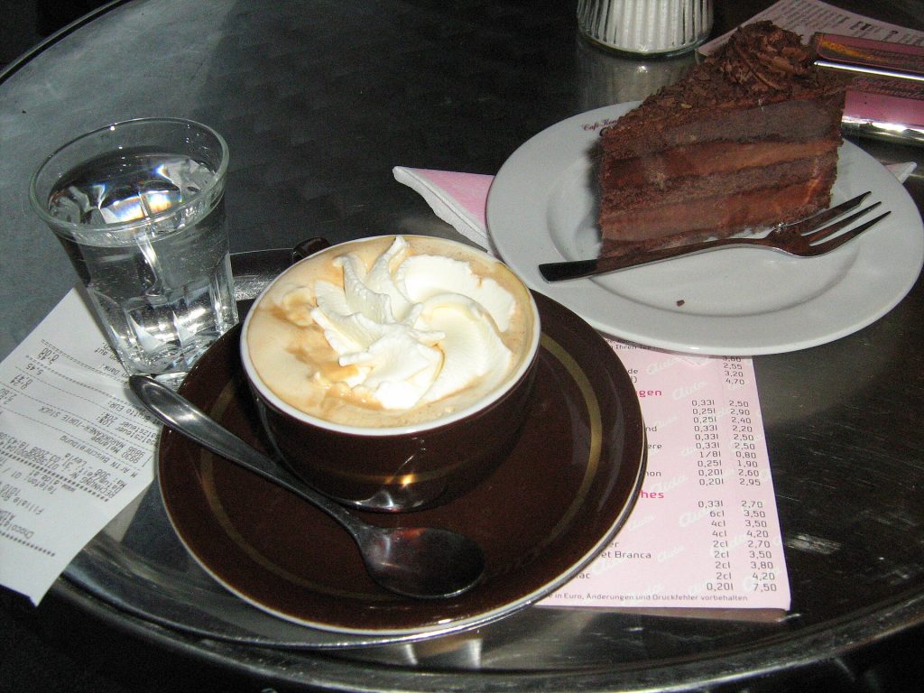 Viennese coffee and a slice of Sachertorte cake on a café table